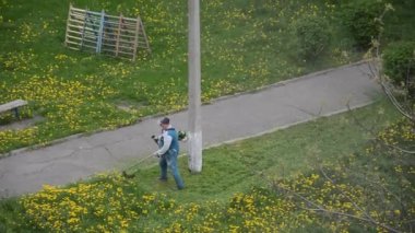 Yaşlı bir adam bahçede bir benzin makası biçiyor.