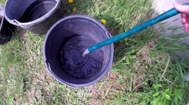 Water pouring from a well into plastic buckets