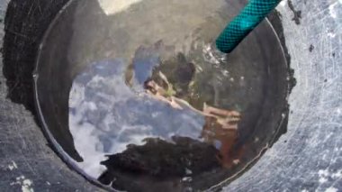 Water pouring from a well into plastic buckets