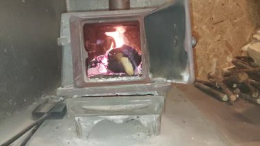 Odun yanan dökme demir bir soba evi ısıtıyor.