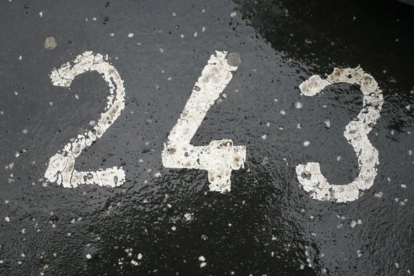 Номер парковки покрашен в белый цвет на асфальте 243 — стоковое фото