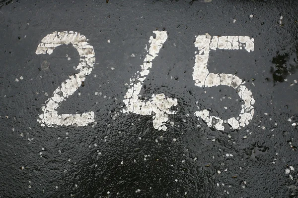 Номер парковки пофарбований в білий колір на асфальті 245 — стокове фото