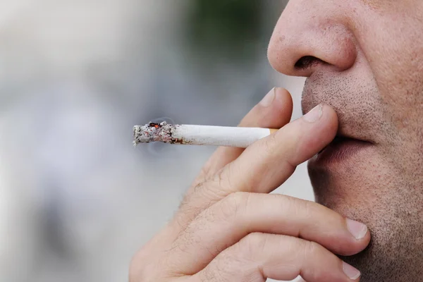 Człowiek twarz gospodarstwa papierosa i palenie — Zdjęcie stockowe