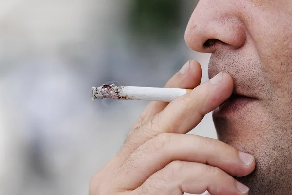 Hombre cara celebración de cigarrillo y fumar — Foto de Stock