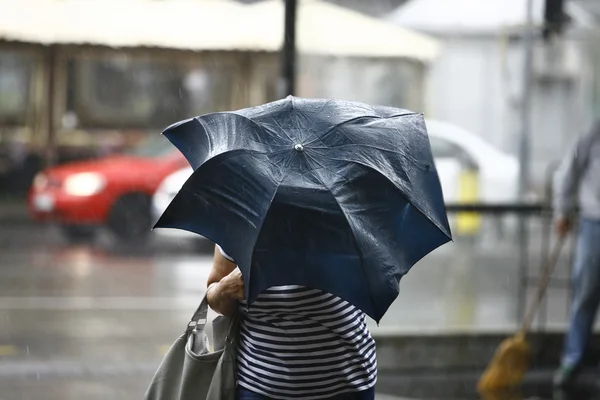 Donna che cammina con gli ombrelli nella città piovosa — Foto Stock