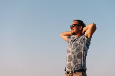 Sarışın adam yaz gündoğumunda deniz kenarında dinleniyor..