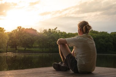 Sarışın adam yazın gün ışığında gölde dinleniyor..
