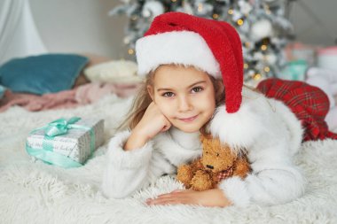 Noel Baba şapkalı çocuk Noel ağacının arka planında.