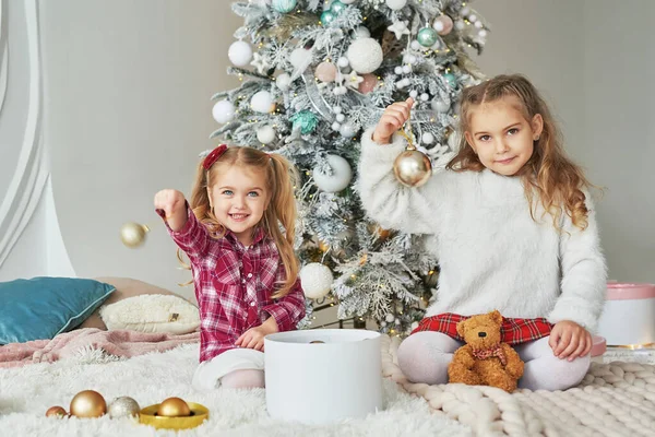 Arka plandaki Noel ağacında iki kız kardeş. Mutlu bir aile. Arkadaşlık kavramı.
