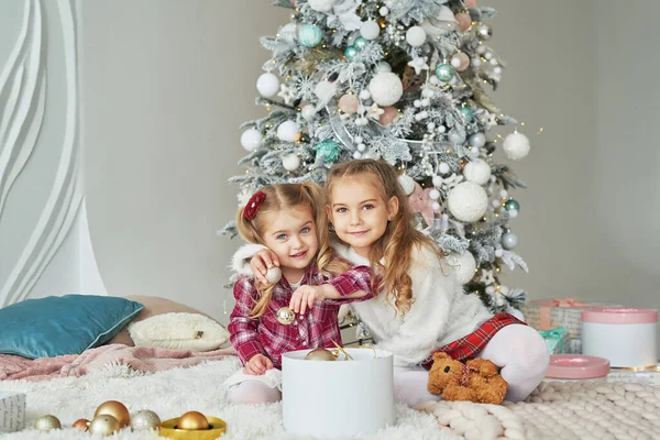 Arka plandaki Noel ağacında iki kız kardeş. Mutlu bir aile. Arkadaşlık kavramı.