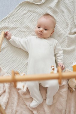 Yeni doğmuş bebek yalan söyler ve eğitici oyuncaklarla oynar. Anneliğin ve babalığın kutlu olsun. Doğum hastanesi ve kliniği. Babalar günü. Erken çocukluk gelişimi.