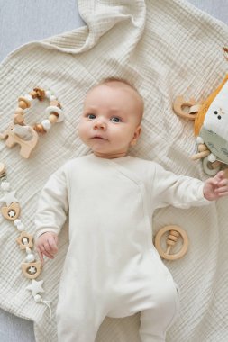 Yeni doğmuş bebek yalan söyler ve eğitici oyuncaklarla oynar. Anneliğin ve babalığın kutlu olsun. Doğum hastanesi ve kliniği. Babalar günü. Erken çocukluk gelişimi.