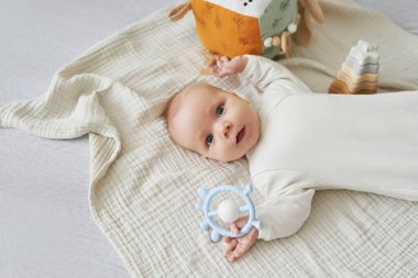 Yeni doğmuş bebek yalan söyler ve eğitici oyuncaklarla oynar. Anneliğin ve babalığın kutlu olsun. Doğum hastanesi ve kliniği. Babalar günü. Erken çocukluk gelişimi.