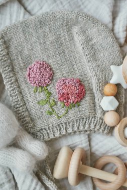 Hobiler ve el sanatları. El yapımı nakışla örülmüş bir bere. Tahta oyuncaklar, çıngıraklar, ipler, meme ucu tutacağı. Bebek gelişimi, iyi motor beceriler. Çocuklar ve yeni doğan ürünler ve aksesuarlar