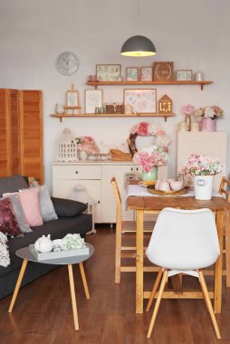 Pembe oturma odası ve mutfak. Stüdyo daire. Çatı katı. Raflar ve bahar dekorları odada. Kiralama ve konut teslimatı. Pansiyon ve otel.