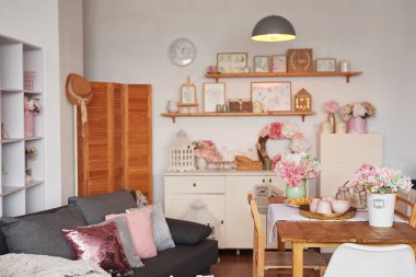 Pembe oturma odası ve mutfak. Stüdyo daire. Çatı katı. Raflar ve bahar dekorları odada. Kiralama ve konut teslimatı. Pansiyon ve otel.