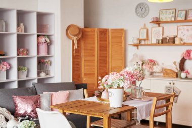 Pembe oturma odası ve mutfak. Stüdyo daire. Çatı katı. Raflar ve bahar dekorları odada. Kiralama ve konut teslimatı. Pansiyon ve otel.