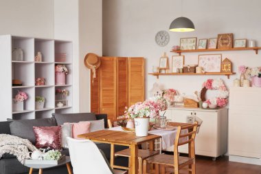 Pembe oturma odası ve mutfak. Stüdyo daire. Çatı katı. Raflar ve bahar dekorları odada. Kiralama ve konut teslimatı. Pansiyon ve otel.