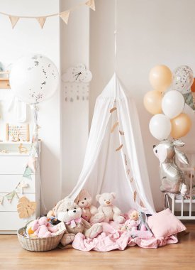 İskandinav tarzı beyaz iç mekan çocuk odası, yatak odası, çocuk odası. Kanopili bebek karyolası. Ahşap raflar ve oyuncaklar. Tente çadırı, tekstil uçurtması ve balonlar.