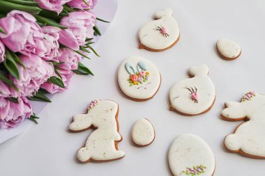 Paskalya kompozisyonu, tatlı ekmek, zencefilli tavşan ve yumurta, bir buket çiçek lalesi. Tatil kahvaltısı. Geleneksel Paskalya zencefilli kurabiye. Paskalya tebrik kartı şablonu.