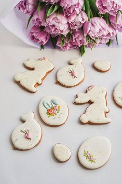 Paskalya kompozisyonu, tatlı ekmek, zencefilli tavşan ve yumurta, bir buket çiçek lalesi. Tatil kahvaltısı. Geleneksel Paskalya zencefilli kurabiye. Paskalya tebrik kartı şablonu.