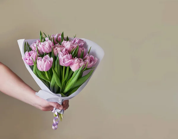 Bouquet of flowers pink tulips in hand. Flower delivery. Happy Birthday! Spring background. Mother's Day