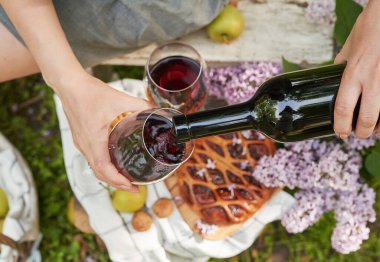 Bahçede yaz pikniği. Şarap, turta, meyve ve çiçekler. Durgun hayat. Paskalya yemeği ve masa. Bir kadının elleri şarap bardağını dolduruyor..