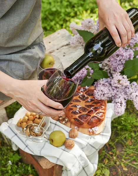 Bahçede yaz pikniği. Şarap, turta, meyve ve çiçekler. Durgun hayat. Paskalya yemeği ve masa. Bir kadının elleri şarap bardağını dolduruyor..