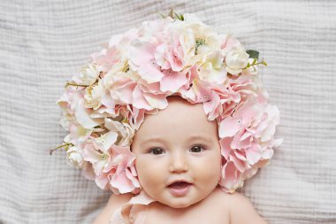 Çiçek şapkalı bebek. Anneler Günü ve Paskalya kartı. Çocuk Koruma Günü. Dünya Mutluluk Günü. Gülümseyen çocuk.