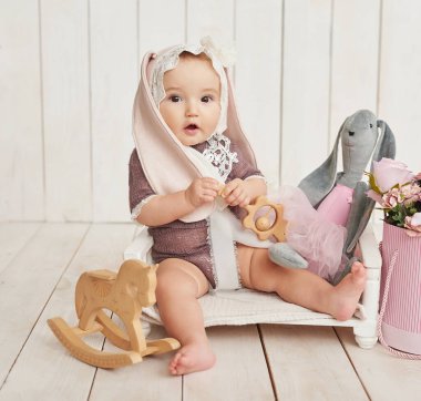 Hasır sepette kulakları ve tahta oyuncakları olan şapkalı bir bebek. Anneler Günü ve Paskalya kartı. Çocuk Koruma Günü. Dünya Mutluluk Günü. Gülümseyen çocuk