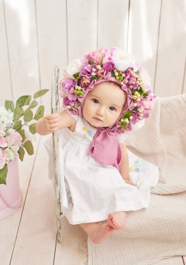 Çiçek şapkalı bebek. Anneler Günü ve Paskalya kartı. Çocuk Koruma Günü. Dünya Mutluluk Günü. Gülümseyen çocuk.