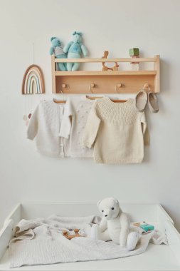 Children's knitted clothes. Shelf with hanger. Cardigan, sweater, jumper on hanger. Children's room, nursery.