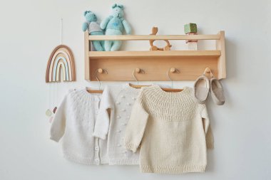 Children's knitted clothes. Shelf with hanger. Cardigan, sweater, jumper on hanger. Children's room, nursery.