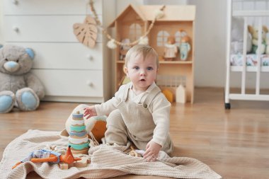 Mavi gözlü harika bir erkek bebek. Çocuk, çocuk odasında oyuncaklarla oynuyor. Erken gelişim, anaokulu, kreş, oyun odası. Çocuk Günü, Anneler Günü.