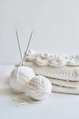 Yığınla örgü elbise, iplik yumakları, örgü şişleri, örmek için aksesuarlar. Bebek kıyafetleri. İğne, hobi, örgü, el işi.