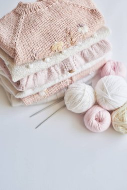 Yığınla örgü elbise, iplik yumakları, örgü şişleri, örmek için aksesuarlar. Bebek kıyafetleri. İğne, hobi, örgü, el işi.