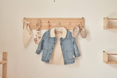 Askıya asılmış çocuk örgüsü. Kot ceket, kazak, şapka, ayakkabı. Çocuk odası, çocuk odası.