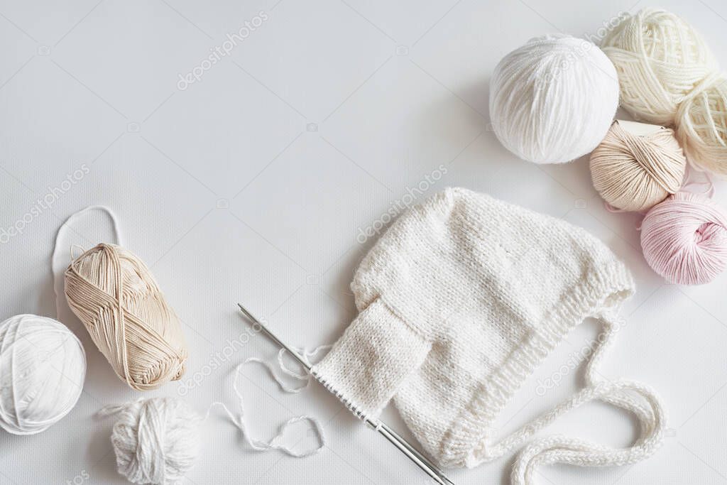 Process of knitting baby hat. Skeins of yarn, knitting needles, accessories for knitting. Handmade, hobby.