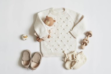 Children's knitwear. Jumper, hat, booties, socks. Wooden teether, nipple. Baby shower party. Preparing for childbirth. Flat lay