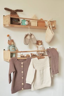 Askıya asılmış çocuk örgüsü. Ceket, kazak, şapka, ayakkabı. Oyuncaklar. Çocuk odası, çocuk odası..