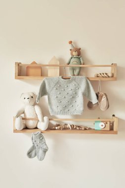 Children's knitted clothes on hanger. Jacket, jumper, hat, shoes. toys. Children's room, nursery.