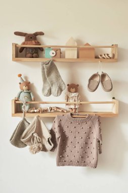 Askıya asılmış çocuk örgüsü. Ceket, kazak, şapka, ayakkabı. Oyuncaklar. Çocuk odası, çocuk odası..