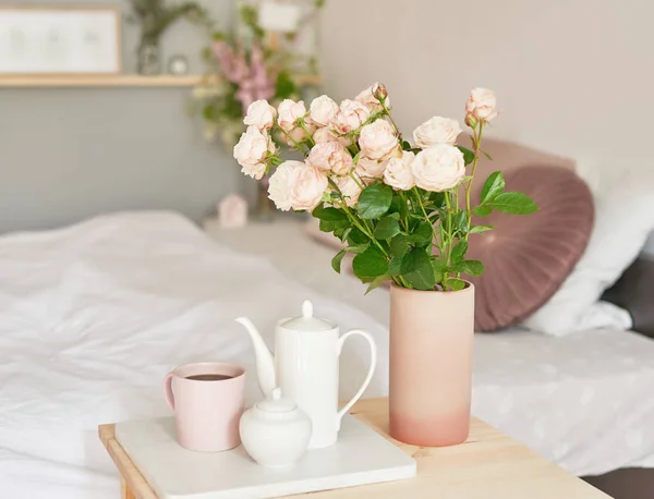 Good cozy morning. Bouquet of rose flowers in vase on table. Hotel room with bed. Check in hotel. Rest and relaxation. Coffee in bed. Romantic breakfast. Valentine\'s Day.