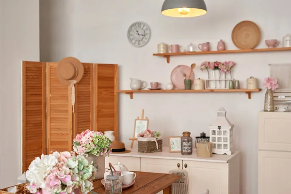 White kitchen interior in loft style. Shelves with pink crockery and kitchen utensils. Studio apartment. Rent and delivery of housing. Hostel and hotel.