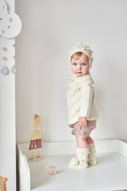 Çocuk odasında örgü şapkalı bebek. Çocuk odasının içinde. Çocuk kıyafetleri ve aksesuarları..