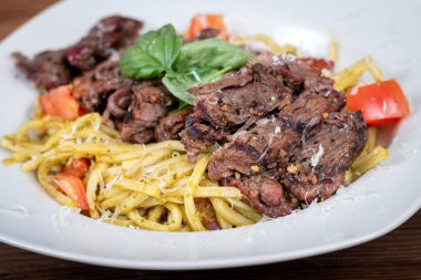 Grilled flank steak over basil pesto and tomato keto pasta dish