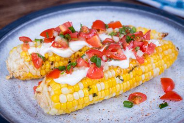 Elote lezzetli ızgara Meksika mısırı krem peynirli ve pico de gallo salsa soslu.