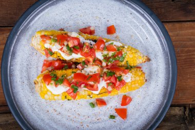 Elote lezzetli ızgara Meksika mısırı krem peynirli ve pico de gallo salsa soslu.