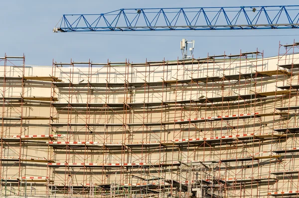 Construção de um edifício moderno com andaimes e guindaste — Fotografia de Stock