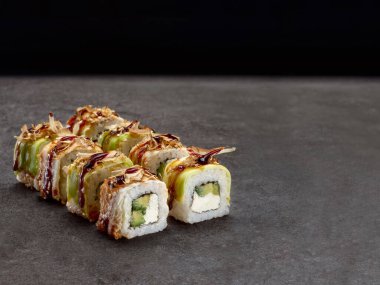 İçinde krem peynir ve avokado olan Japon suşisi rulosu. Koyu beton arka planda unagi yılanbalığı olan Asya yemeği parçaları. Uzay resmini kopyala. Tek nesne
